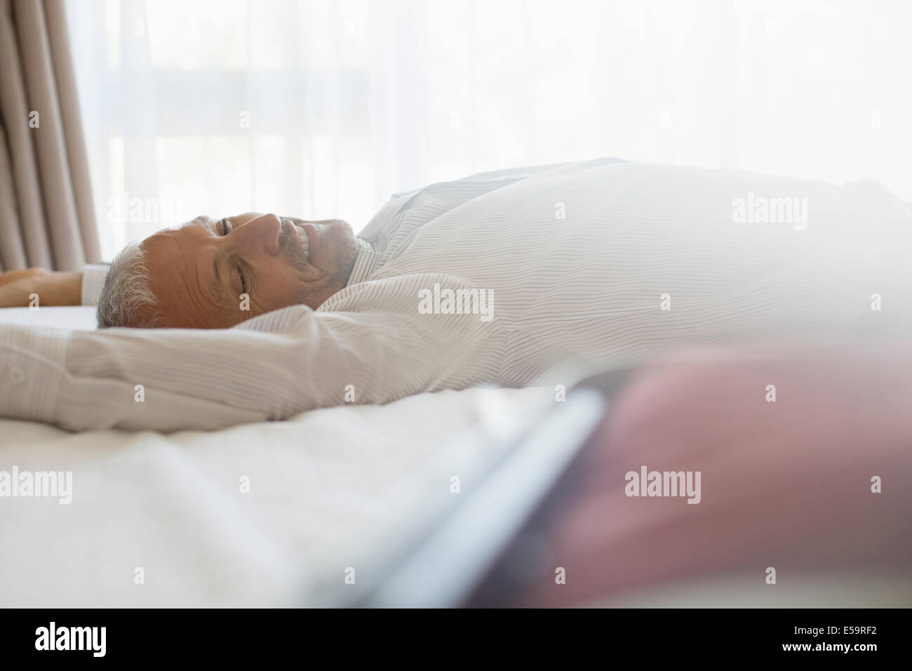 Woman laying on bed in hotel room Banque D'Images