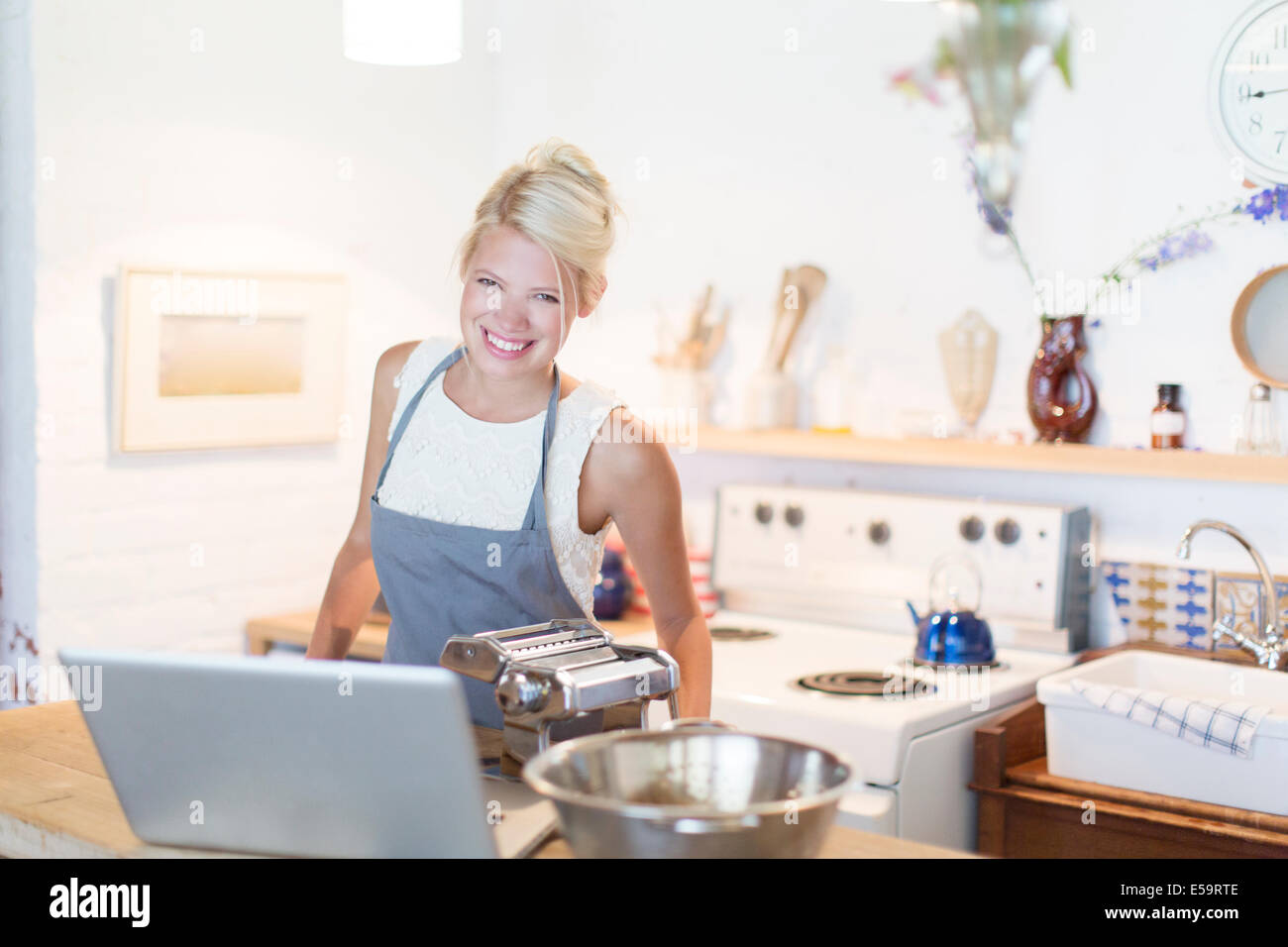 Femme à la cuisson pour ordinateur portable dans la cuisine Banque D'Images