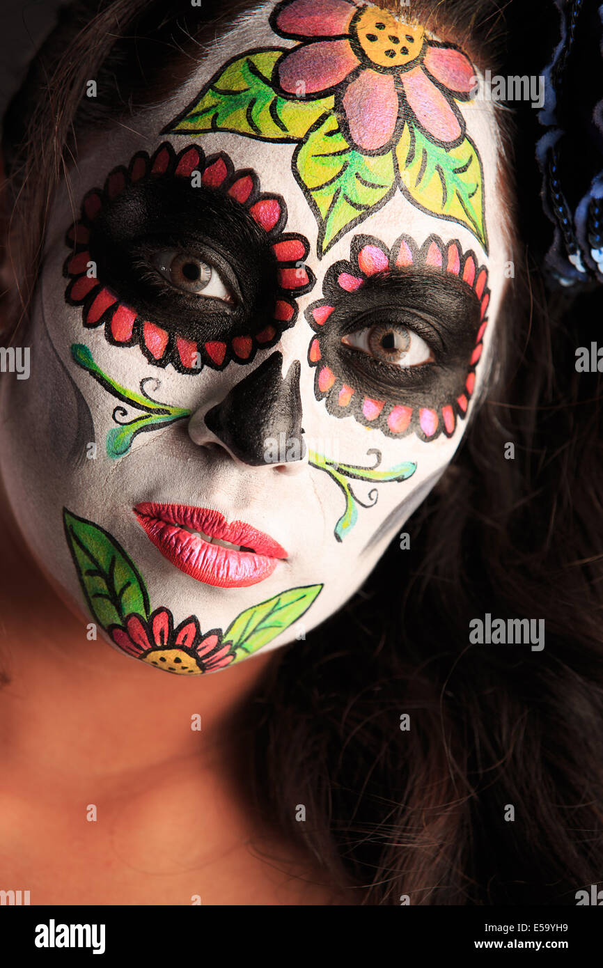 Une jeune femme avec la peinture pour le visage sous la forme d'un crâne en sucre décorée pour Dia de Los Muertos Banque D'Images