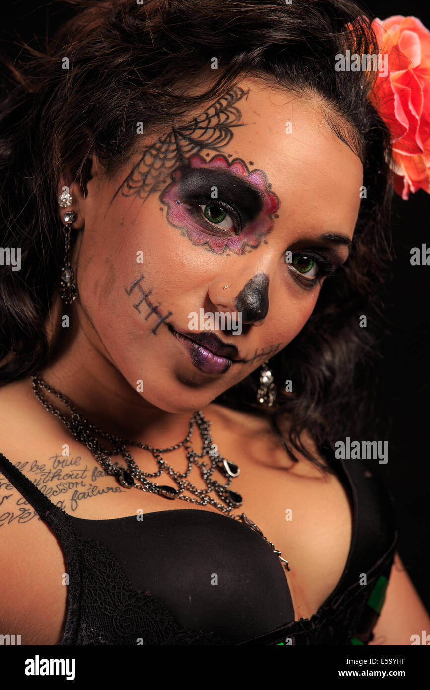 Une jeune femme avec la peinture pour le visage sous la forme d'un crâne en sucre décorée pour Dia de Los Muertos Banque D'Images