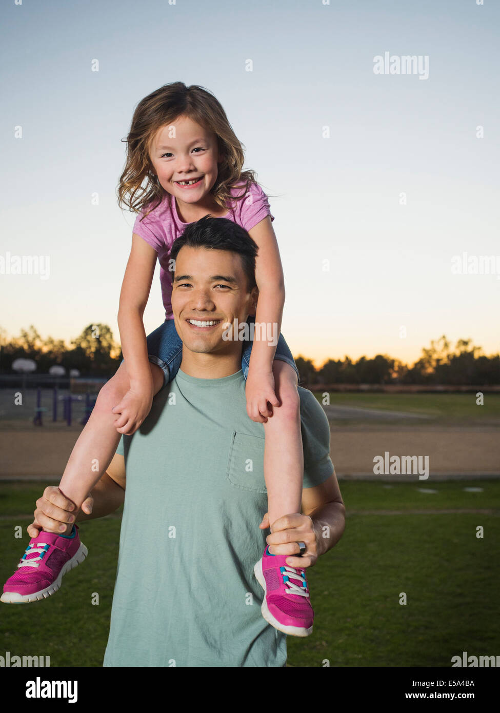 Father carrying daughter on shoulders in park Banque D'Images