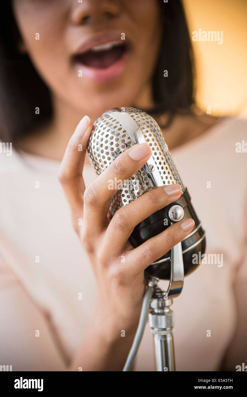 Mixed Race woman singing into microphone vintage Banque D'Images