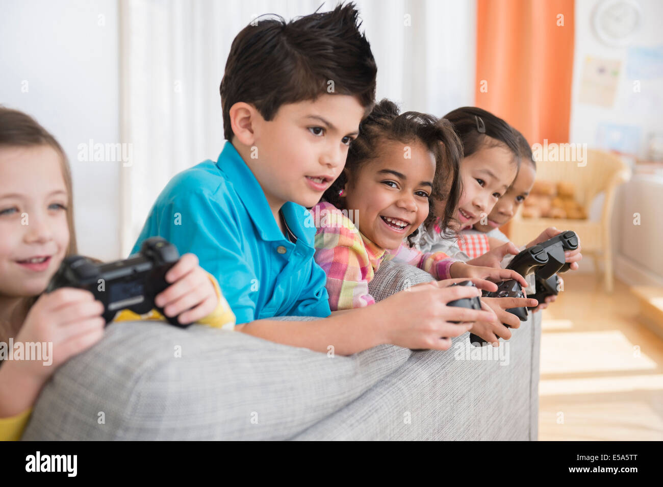 Enfants jouant à des jeux vidéo sur canapé Banque D'Images