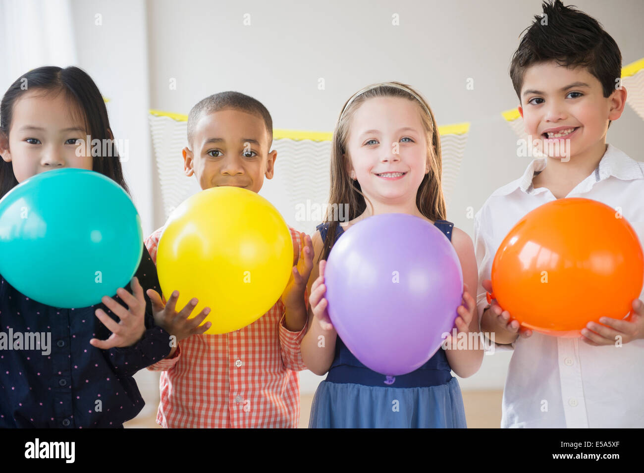 Enfants holding colorful balloons at party Banque D'Images