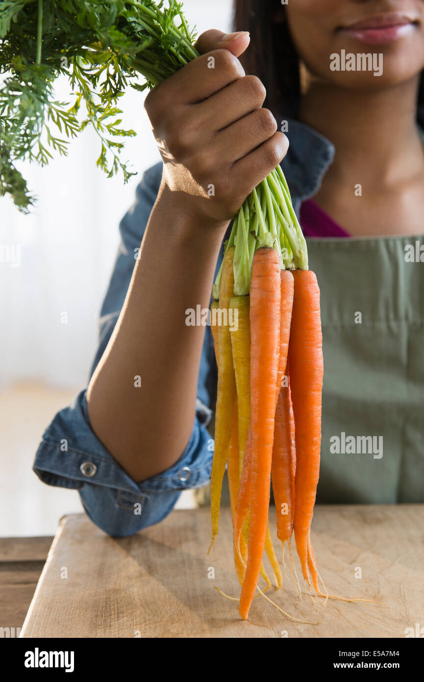 Mixed Race woman holding bunch of carrots Banque D'Images