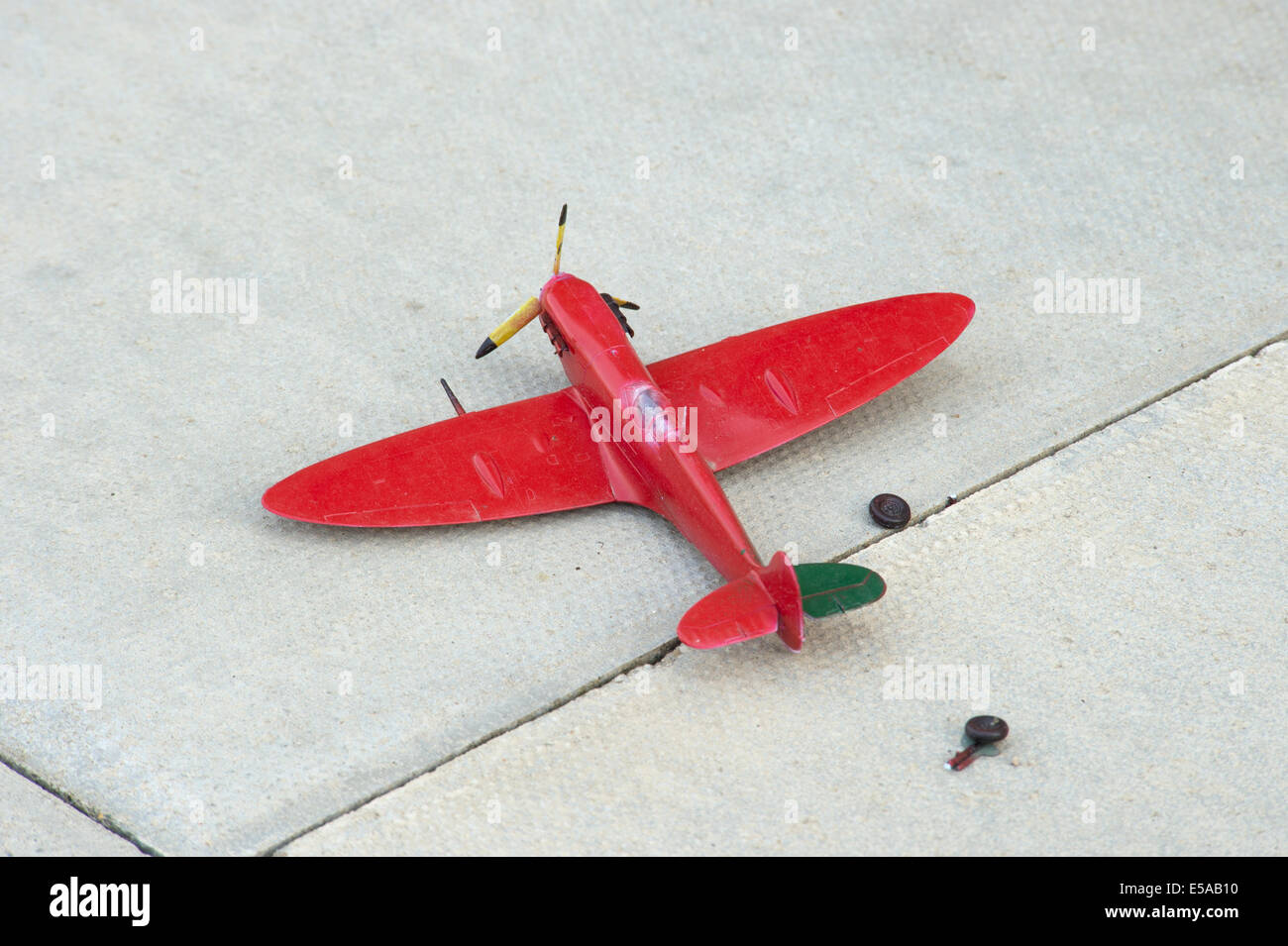 Broken toy rouge avion Spitfire avion train dalle pavage jeter arraché Banque D'Images