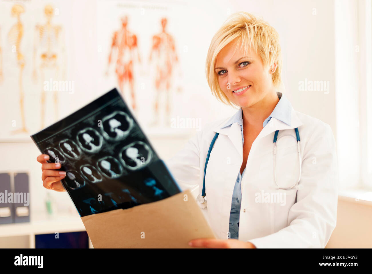 Jeune femme médecin d'ouvrir l'enveloppe avec brain tomography suite, Debica, Pologne Banque D'Images