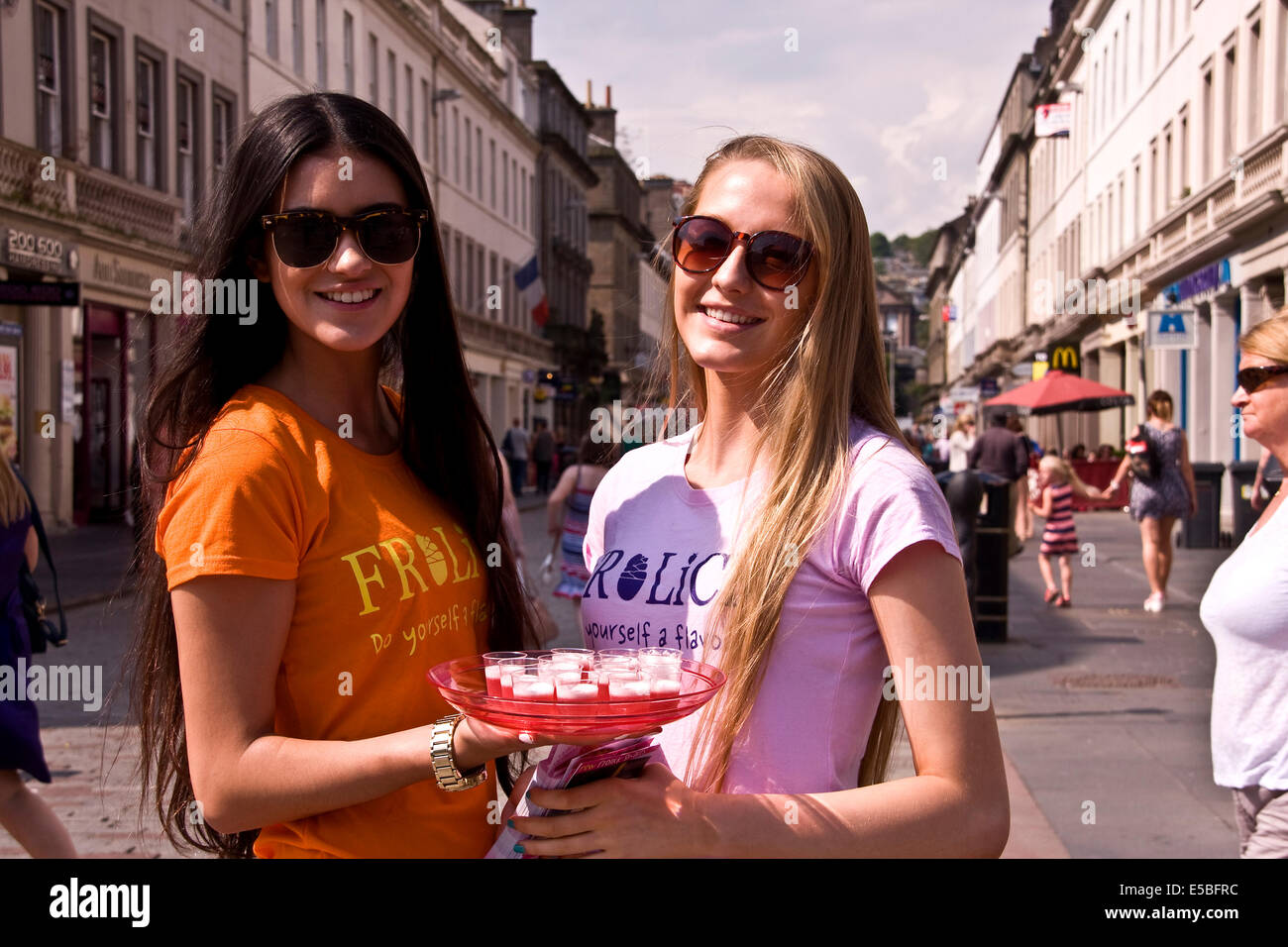 Deux filles de la publicité et la distribution de yaourts glacés FROLICK boissons pendant la canicule de la Dundee, Royaume-Uni Banque D'Images