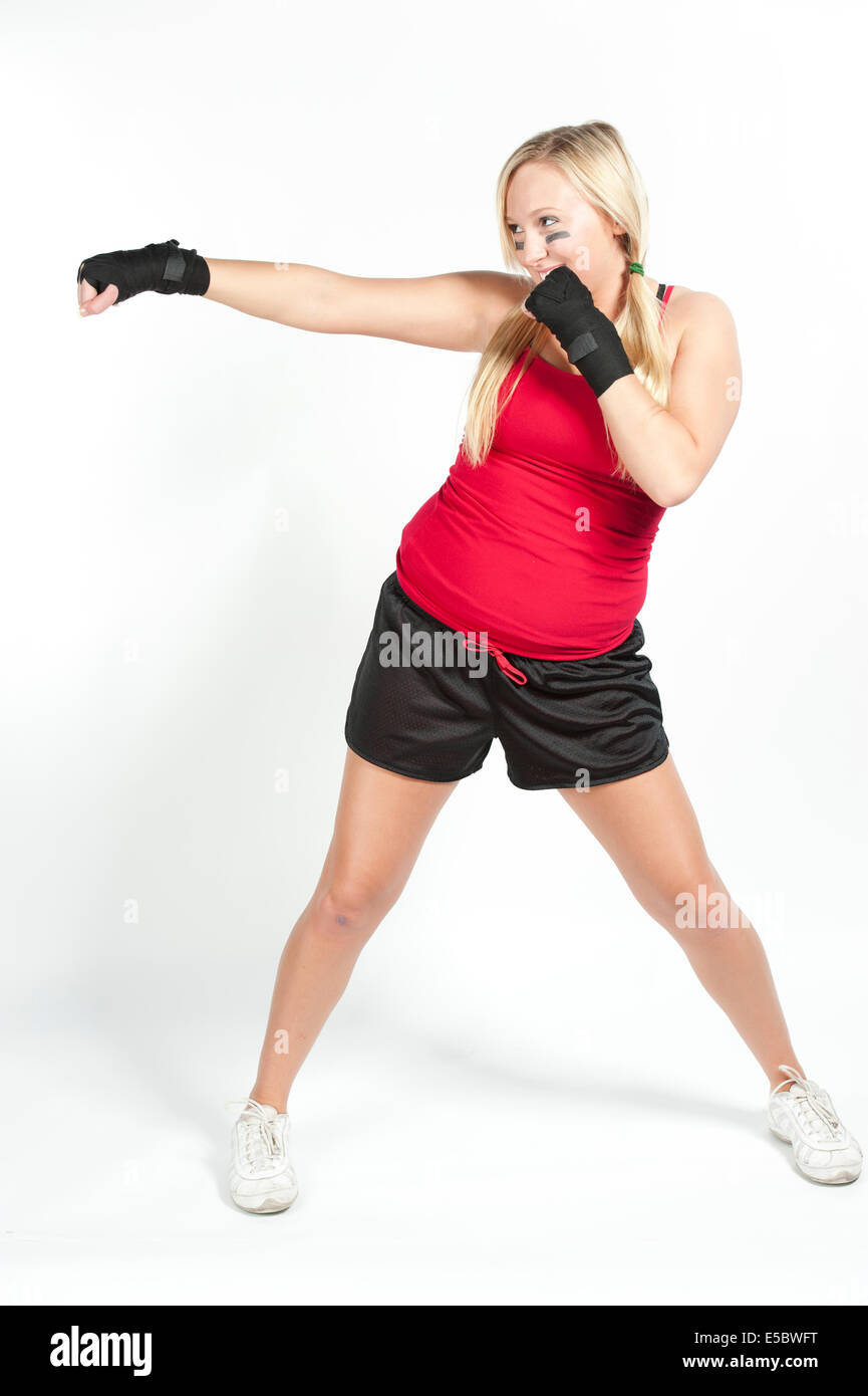 Une jeune fille blonde se prépare à fort wraps boxe vêtu de noir sur un fond blanc portant un t-shirt rouge et short noir. Banque D'Images