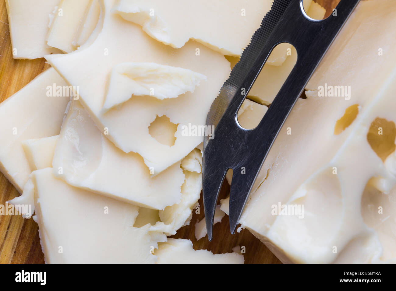 Tranches de fromage blanc maasdam avec couteau sur sol en bois Banque D'Images