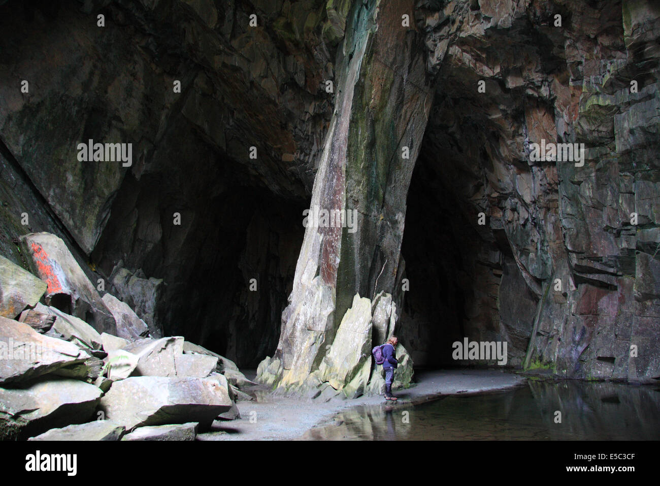Figure féminine solitaire debout dans une caverne à l'homme connu sous le nom de Cathédrale Quarry en peu dans le Langdale Lake District Banque D'Images