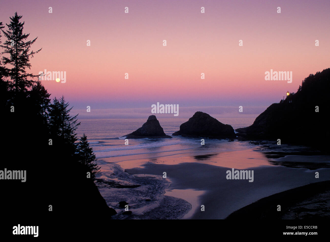 Le phare de Heceta Head et la pleine lune se couche sur l'océan ; Parc d'état de Devils Elbow, côte de l'Oregon. Banque D'Images