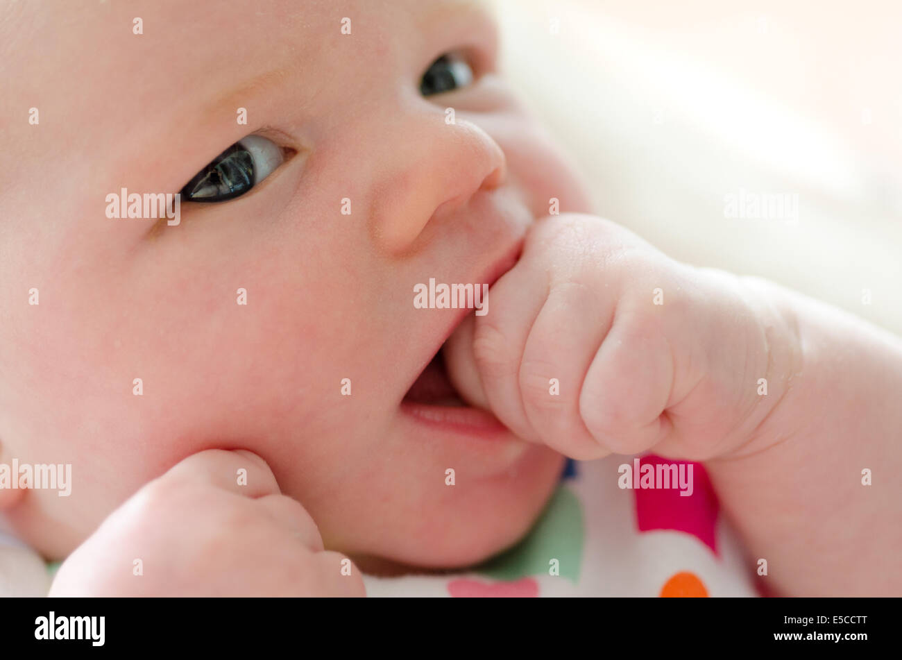 Baby Girl trois semaines mordre fist looking at camera Banque D'Images