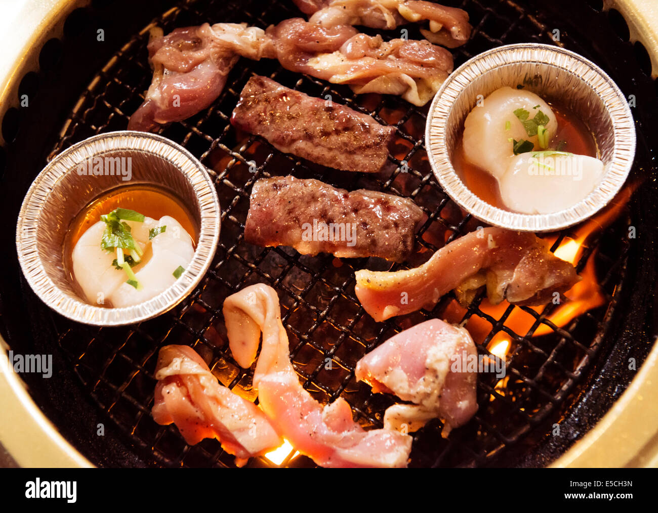 Libre de boeuf et les pétoncles sont cuits sur le feu à un restaurant grill japonais Banque D'Images