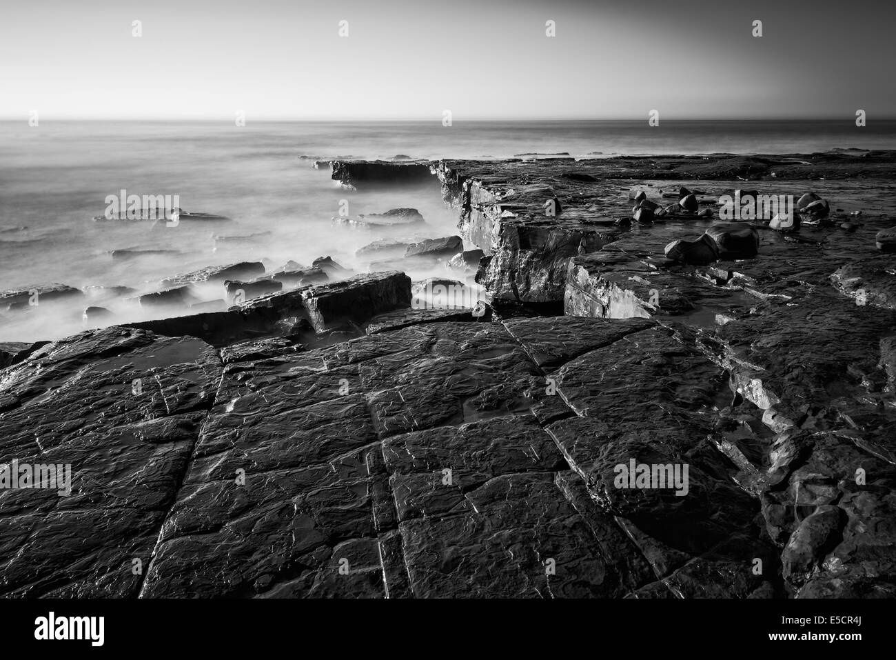 Paysage côtier au lever du soleil avec des falaises et des bougies de Misty en noir et blanc Banque D'Images