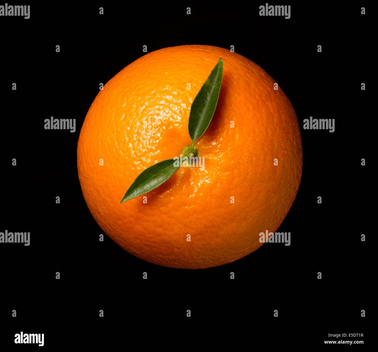 Un coup d'orange sur un fond noir avec les feuilles à la main sur une horloge Banque D'Images