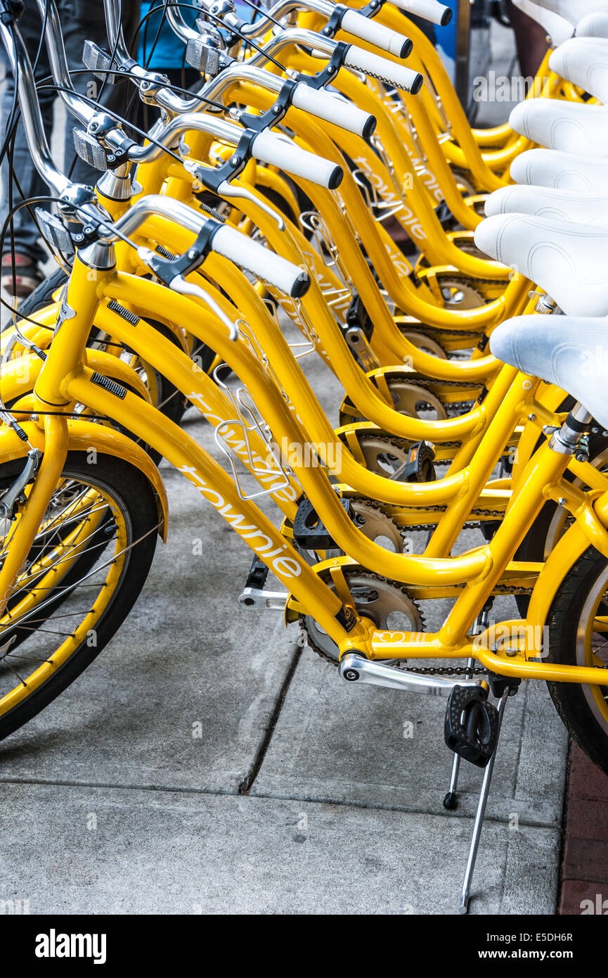 Une ligne d'un service de location de vélos jaunes sur l'affichage pour la transmettre à la foule les jours de marché à Broadway dans le centre-ville de Columbus, Géorgie, USA. Banque D'Images