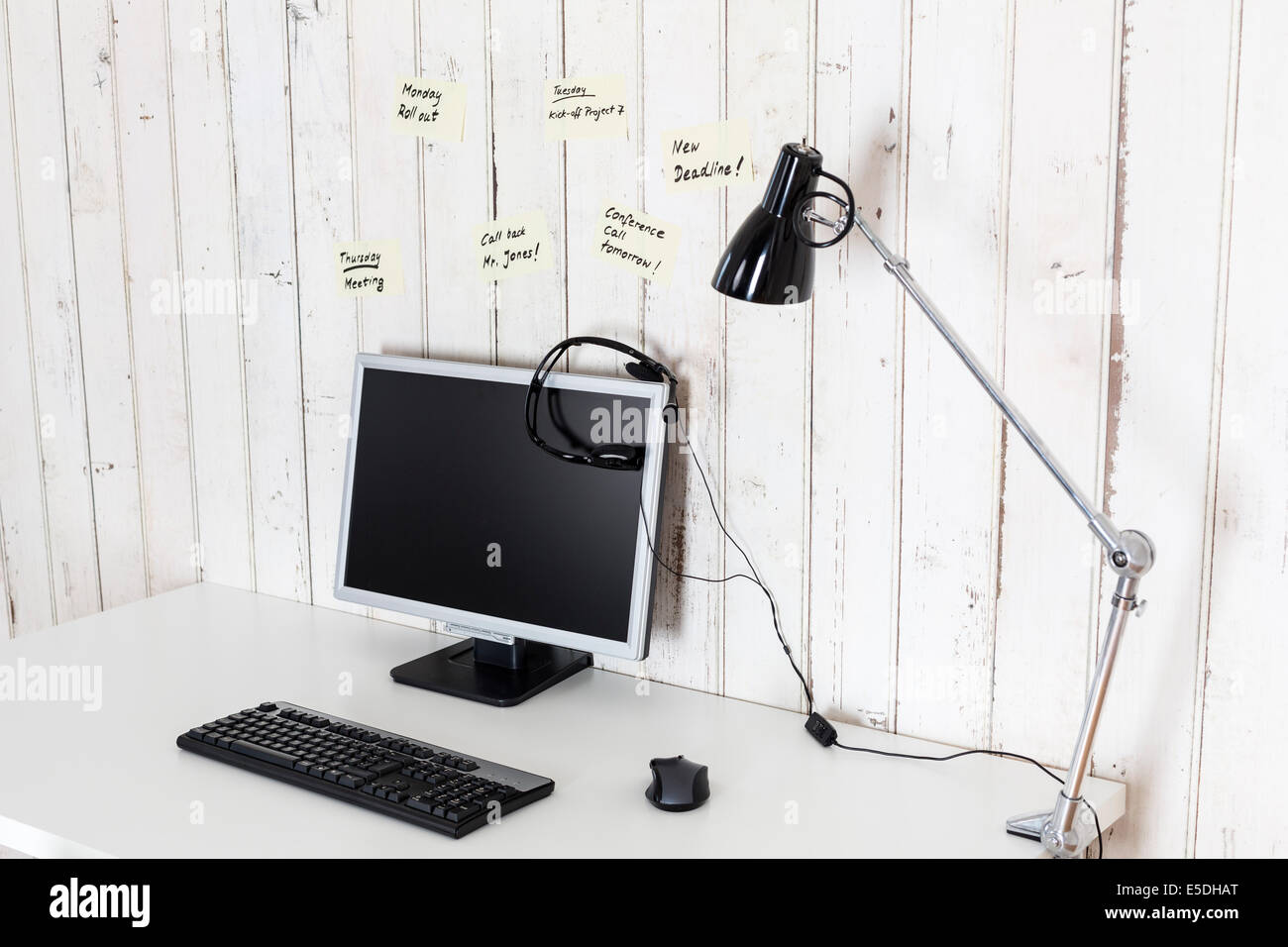 Accueil simple bureau avec ordinateur personnel, le casque et les notes sur le mur Banque D'Images