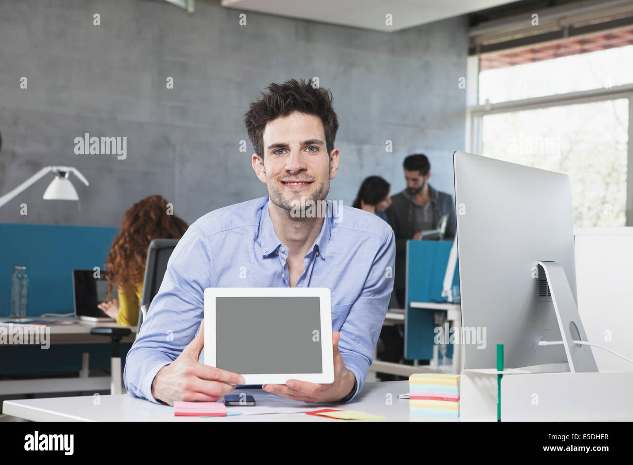 Portrait of smiling man showing tablet ordinateur dans le bureau Banque D'Images
