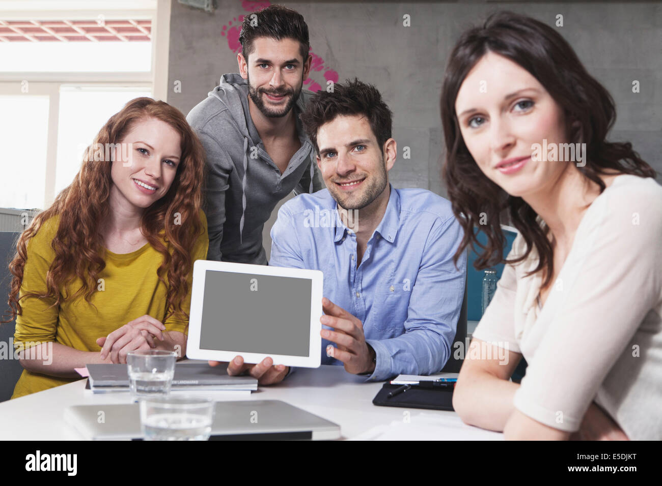 Photo de groupe des quatre personnes créatives montrant dans le bureau de l'ordinateur tablette Banque D'Images