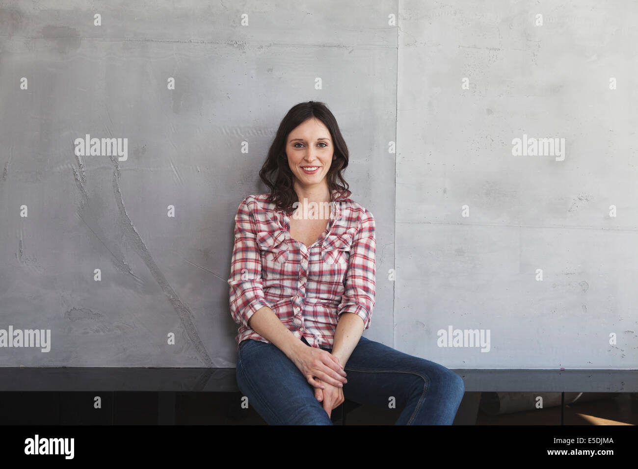 Portrait of smiling woman in front of grey wall Banque D'Images