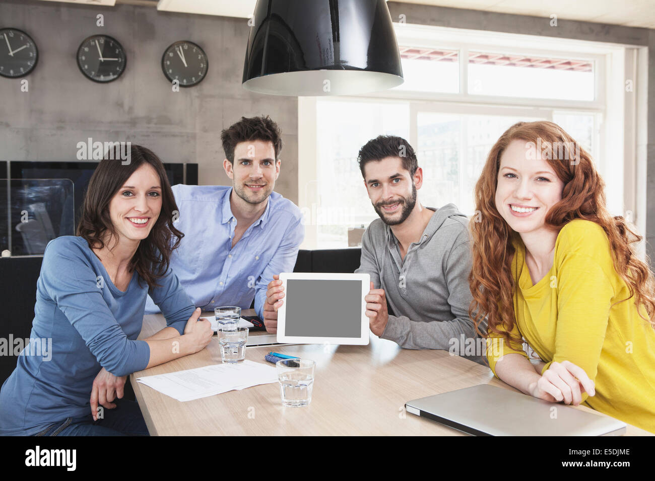 Photo de groupe des quatre personnes créatives montrant dans le bureau de l'ordinateur tablette Banque D'Images