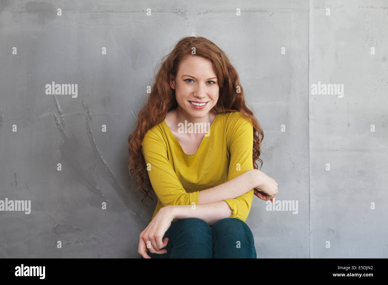 Portrait of smiling woman in front of grey wall Banque D'Images