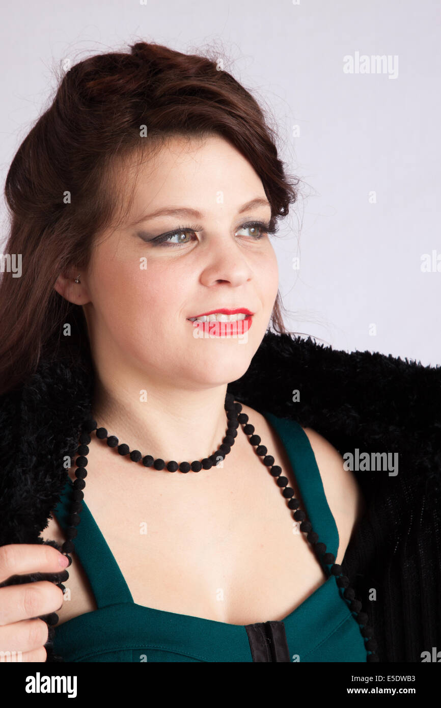 Jolie femme en veste noire et perles noires, souriant avec son blouson ouvert Banque D'Images