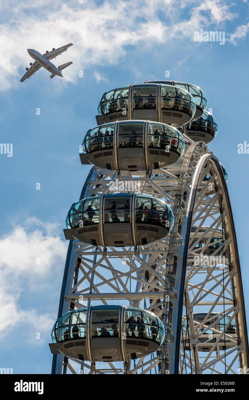 Un avion passe sur le London Eye, une grande roue sur la rive sud de la Tamise à Londres Banque D'Images