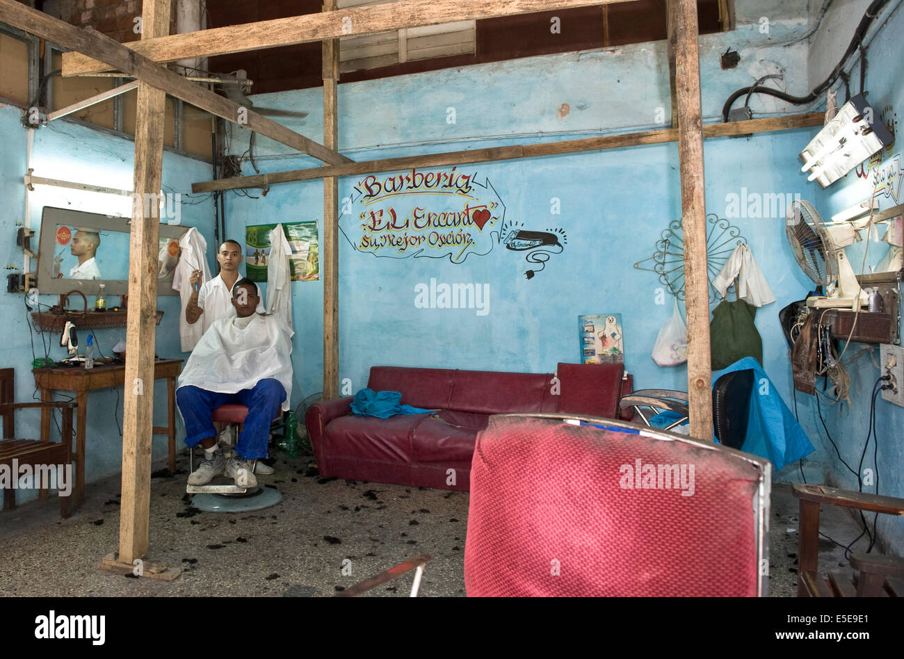 Un salon de coiffure coupe de cheveux d'un client dans son salon de coiffure à court de sa propre maison dans le centre-ville de La Havane, Cuba. Banque D'Images