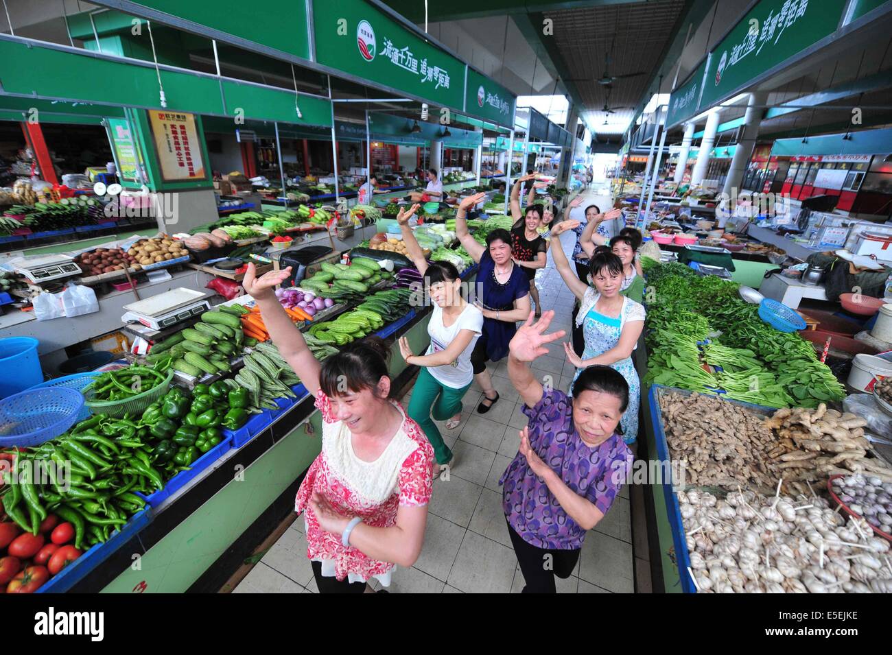 (140730) -- Paris, 30 juillet 2014 (Xinhua) -- concessionnaires femelle danse dans le passage du marché agricole de Sulu à Nanning, capitale de la région autonome Zhuang du Guangxi, le 13 juillet 2014. Les concessionnaires des femmes ici ont profité d'inactivité pour faire de l'exercice physique par la danse. (Xinhua/Huang Xiaobang) (lfj) Banque D'Images