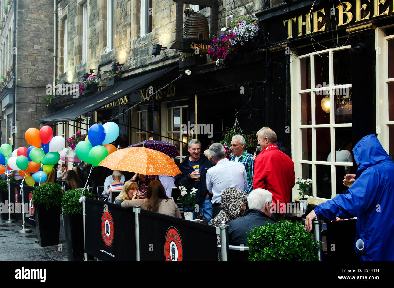 Les gens assis sous la pluie à l'extérieur de l'Beenhive Inn à Édimbourg, en Écosse. Grassmarket. Banque D'Images
