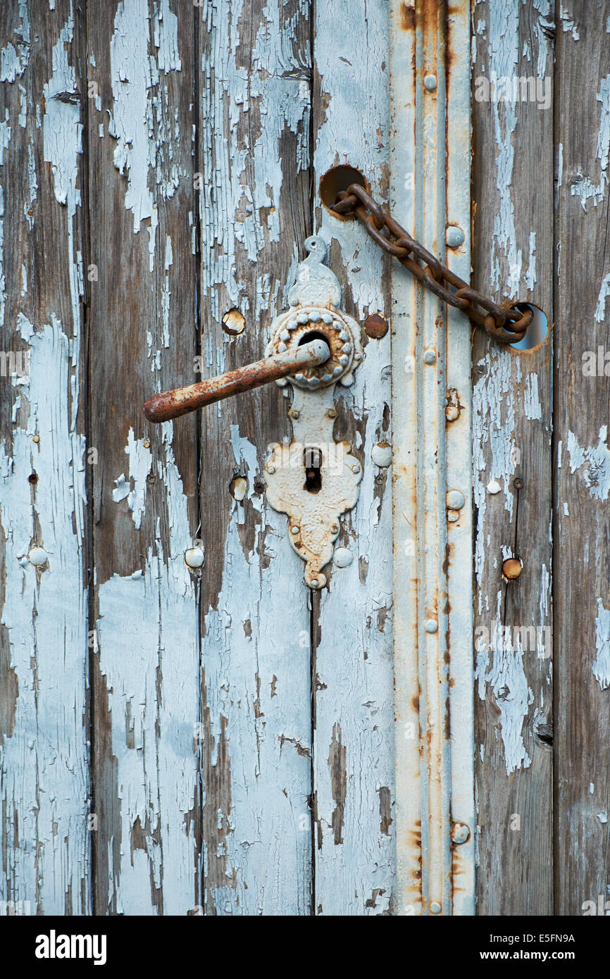 Poignée de porte avec une chaîne rouillée sur une porte en bois patiné Banque D'Images