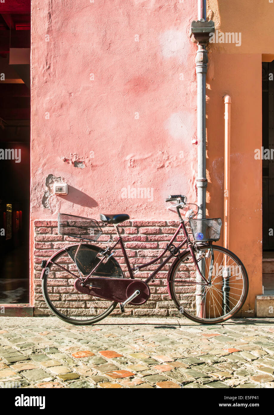 Vieux vélo rouge italienne sur la lumière du soleil. Anciens bâtiments Banque D'Images