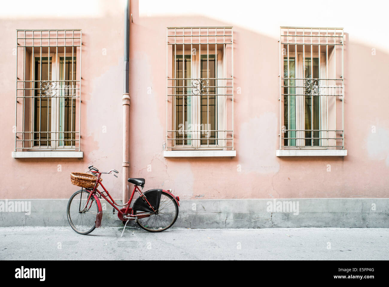 Vieux vélo rouge italienne sur la lumière du soleil. Anciens bâtiments Banque D'Images