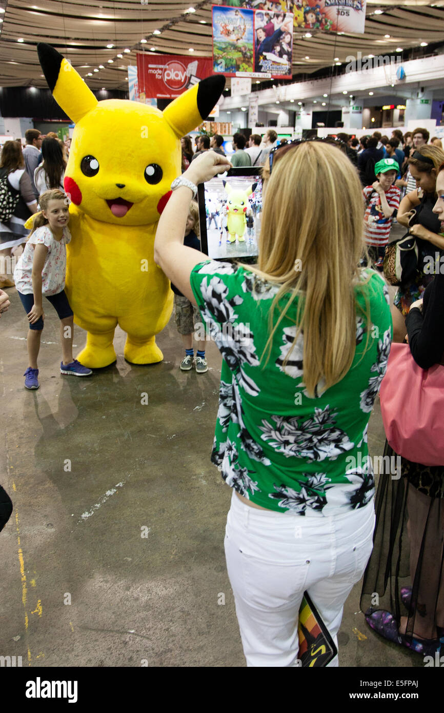 Londres, Angleterre un visiteur au Japon Hyper dans Earls Court prend une photo d'une jeune fille serrant Pikachu avec son iPad. Banque D'Images
