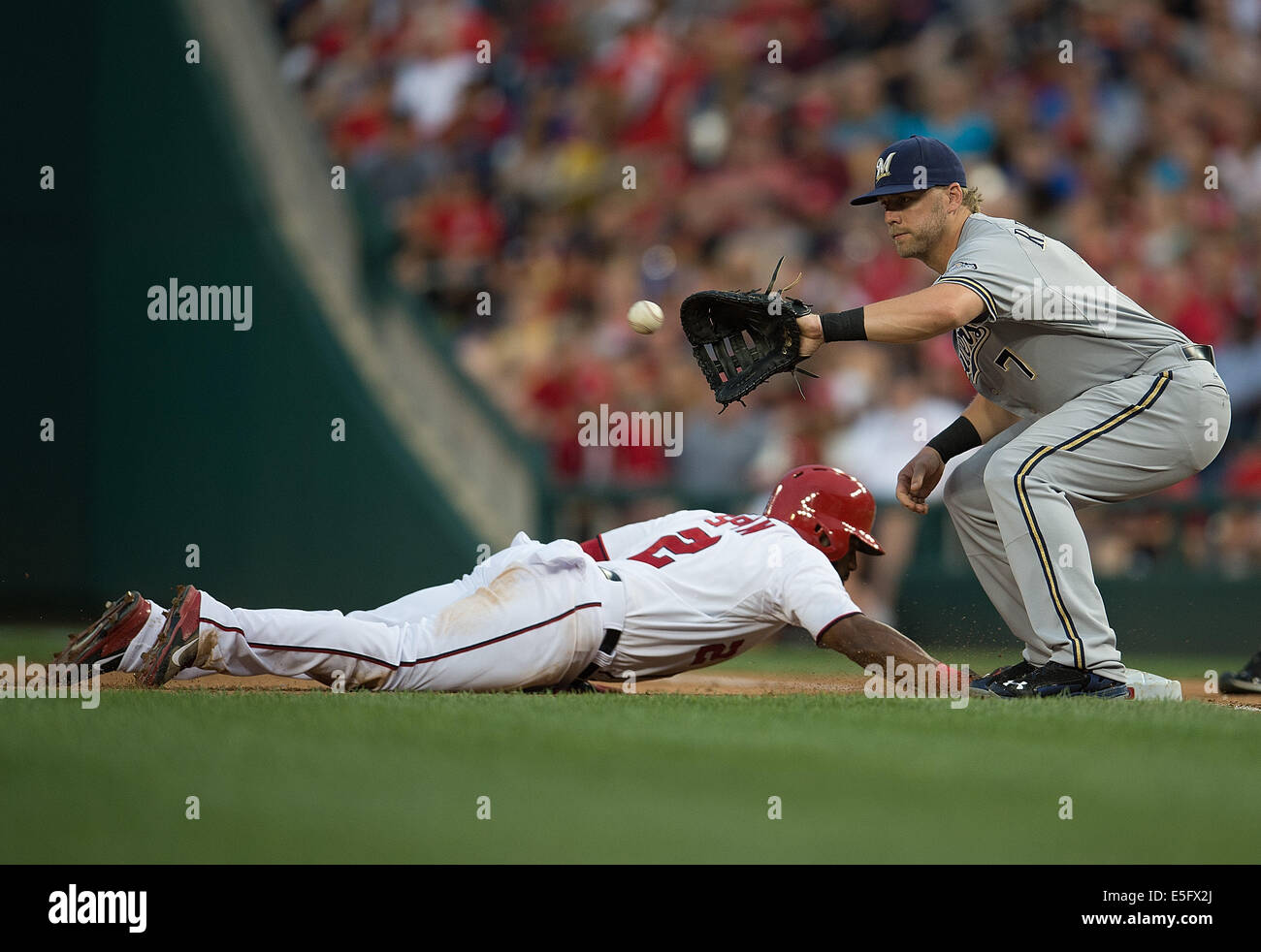 Nationals de Washington center fielder Denard Span (2) plongées en toute sécurité au première base sur une tentative de jeter pickoff premier but des Milwaukee Brewers Mark Reynolds (7) au cours de la troisième manche de leur jeu au Championnat National Park à Washington, D.C, le vendredi 18 juillet 2014.(Photo par Harry E. Walker) Banque D'Images