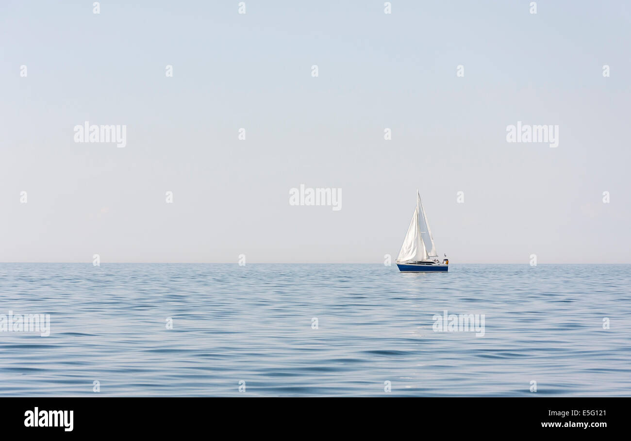 Bateau à voile bleu avec des voiles blanches en mer ou l'océan Banque D'Images