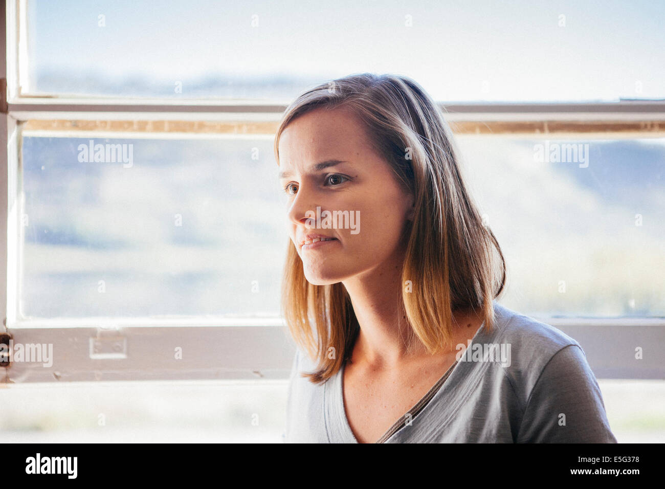 Woman standing by window Banque D'Images