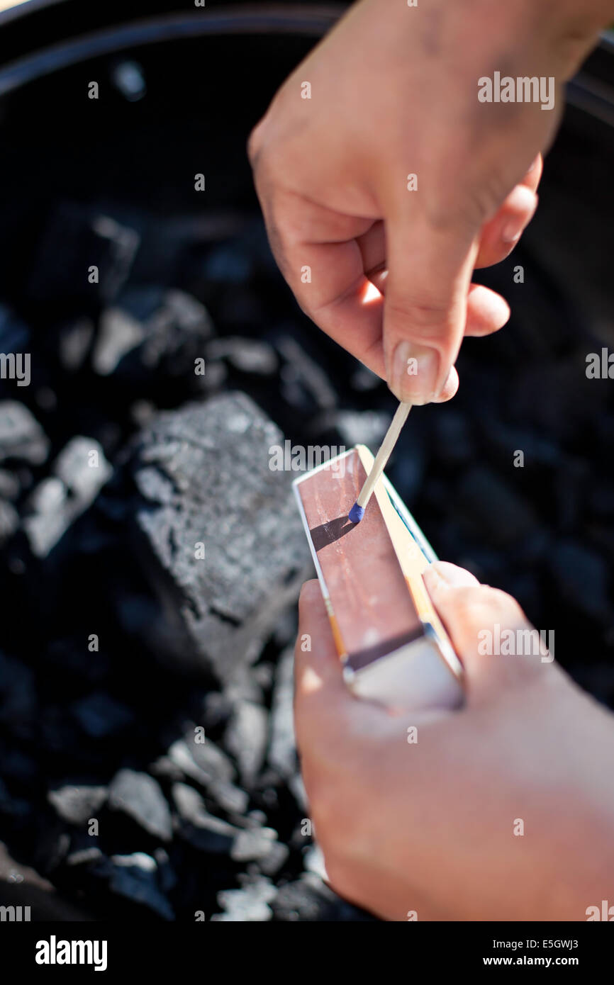Trouver une allumette, brûler un charbon de barbecue, préparer pour la cuisson Banque D'Images