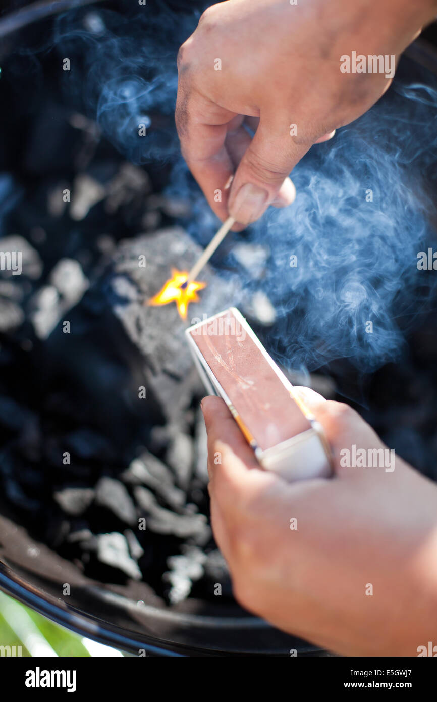 Trouver une allumette, brûler un charbon de barbecue, préparer pour la cuisson, mettre l'accent sur la fumée Banque D'Images