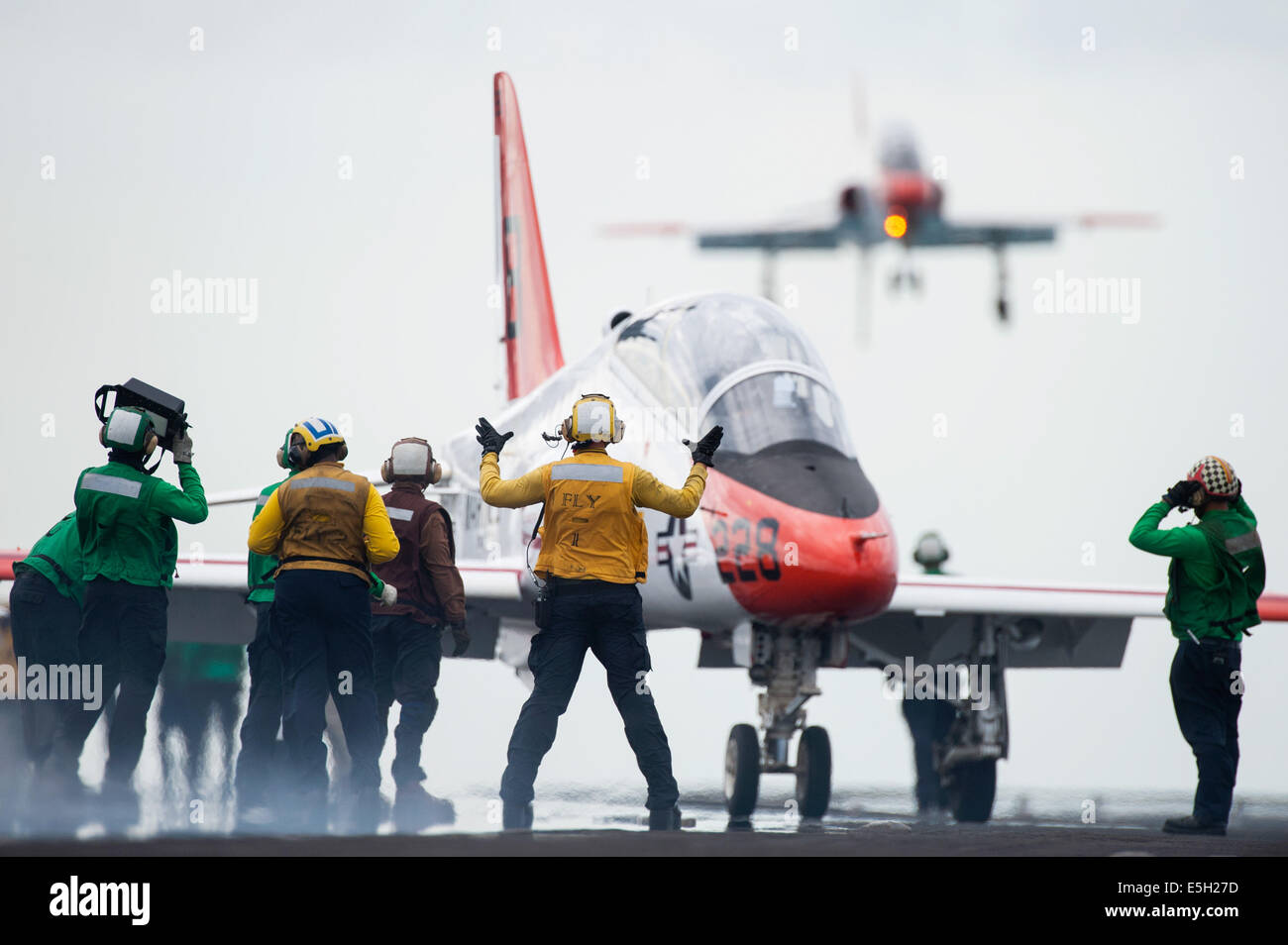 L'aviation de la Marine américaine maître de Manœuvre (manutention) 2e classe Christopher O'Neil, centre, signaux pour le pilote d'un T-45C Goshawk ai Banque D'Images