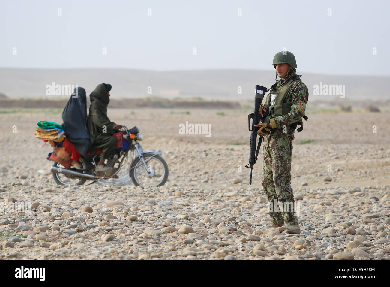 Les civils afghans ride au-delà d'un soldat de l'Armée nationale afghane avec le 4e, 6e Kandak Tolay, 6e Brigade, 215e Corps comme il provi Banque D'Images