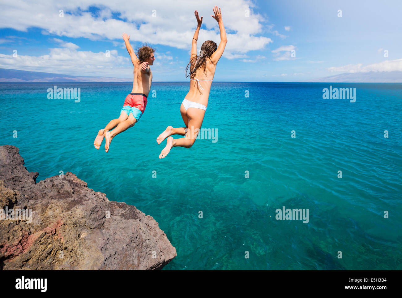 Les amis saut de falaise dans l'océan, d'été en toute vie. Banque D'Images