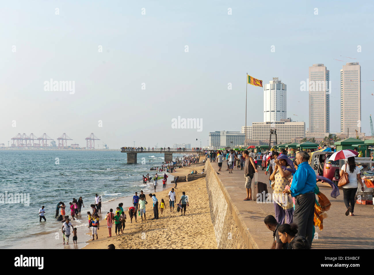 Les gens marchent le long de la promenade de la plage, Galle Face, des gratte-ciel et le port derrière, Colombo, Sri Lanka Banque D'Images