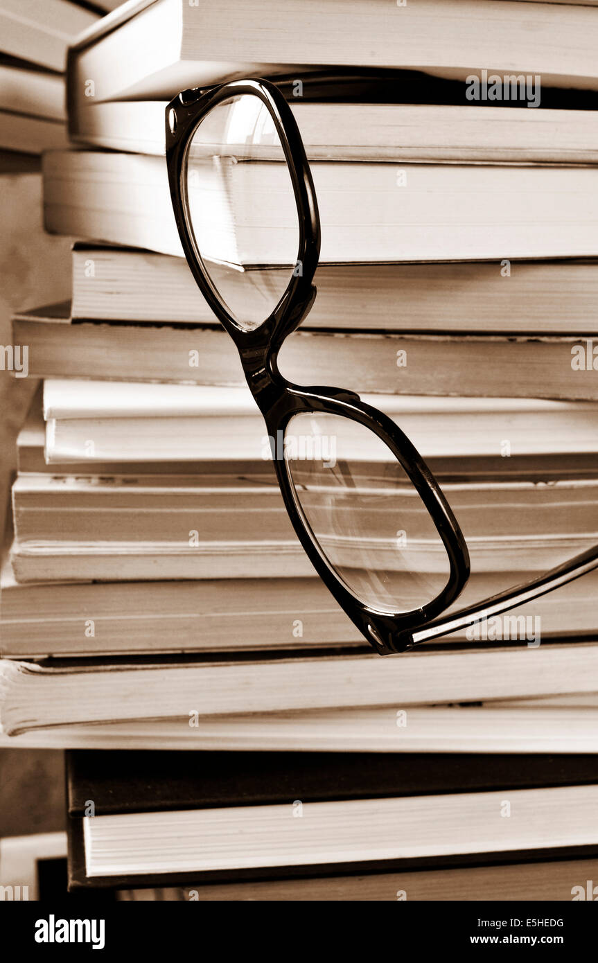 Une paire de lunettes sur une pile de livres, en noir et blanc Banque D'Images
