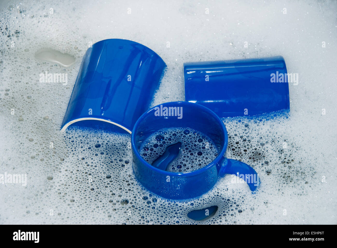 Trois tasses à café bleu dans un évier de cuisine avec lave l'eau et la mousse, Close up Banque D'Images
