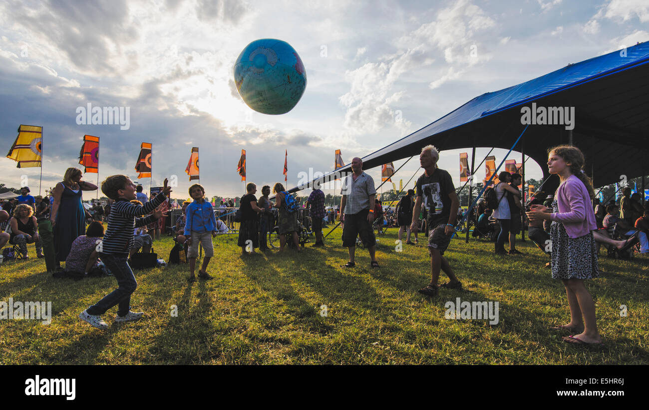 Malmesbury, UK, 25/07/2014 : Atmosphère au monde - WOMAD de la musique, des arts et de la danse. Une famille jouent avec un globe gonflable dans la lumière du soir. Photo par Julie Edwards Banque D'Images