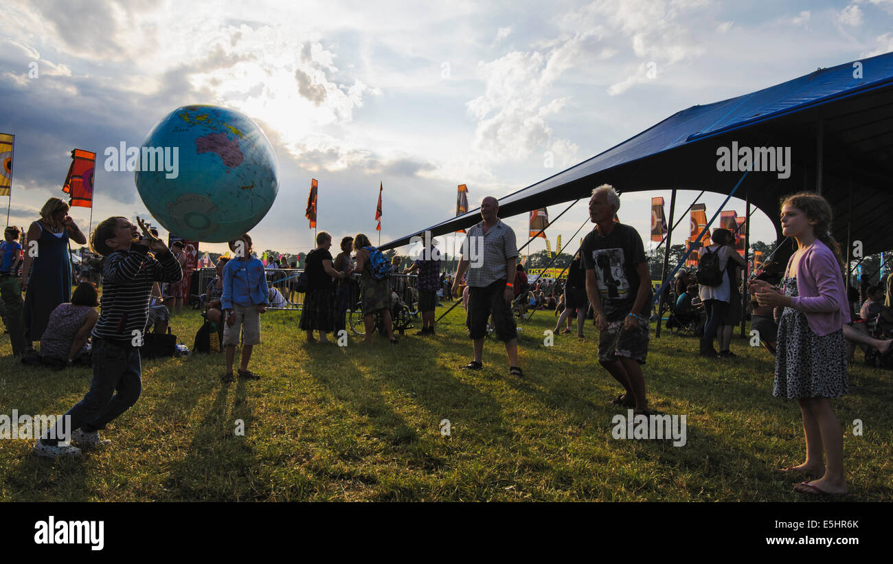 Malmesbury, UK, 25/07/2014 : Atmosphère au monde - WOMAD de la musique, des arts et de la danse. Une famille jouent avec un globe gonflable dans la lumière du soir. Photo par Julie Edwards Banque D'Images