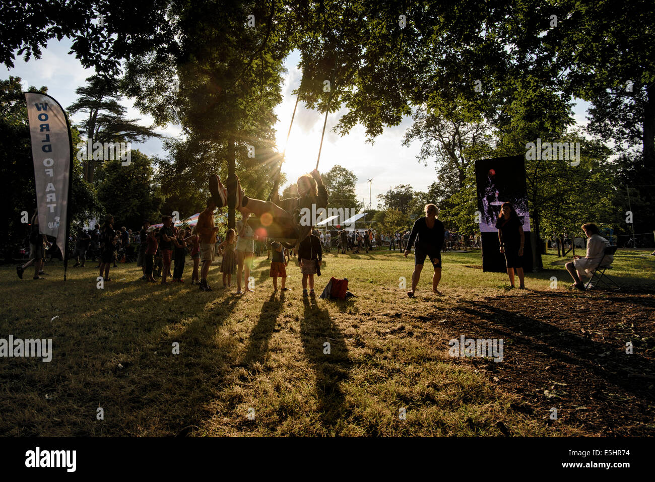 Malmesbury, UK, 25/07/2014 : Atmosphère au monde - WOMAD de la musique, des arts et de la danse. Les enfants jouent n a s'agiter dans les arbres éclairés par un faible soleil du soir. Photo par Julie Edwards Banque D'Images